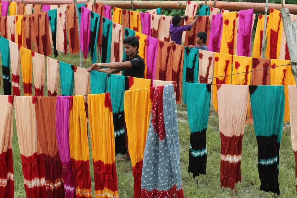 Workers hanging colorful fabrics outdoors in a textile production area